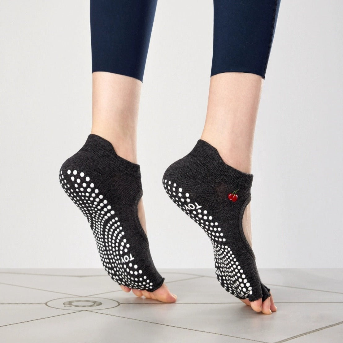 A pair of brown toeless non-slip grip socks with a pattern of white circles on the sole and a red cherry on the ankle support band.