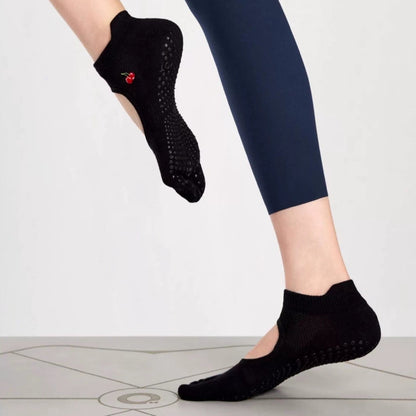 A pair of brown toeless non-slip grip socks with a pattern of white circles on the sole and a red cherry on the ankle support band.