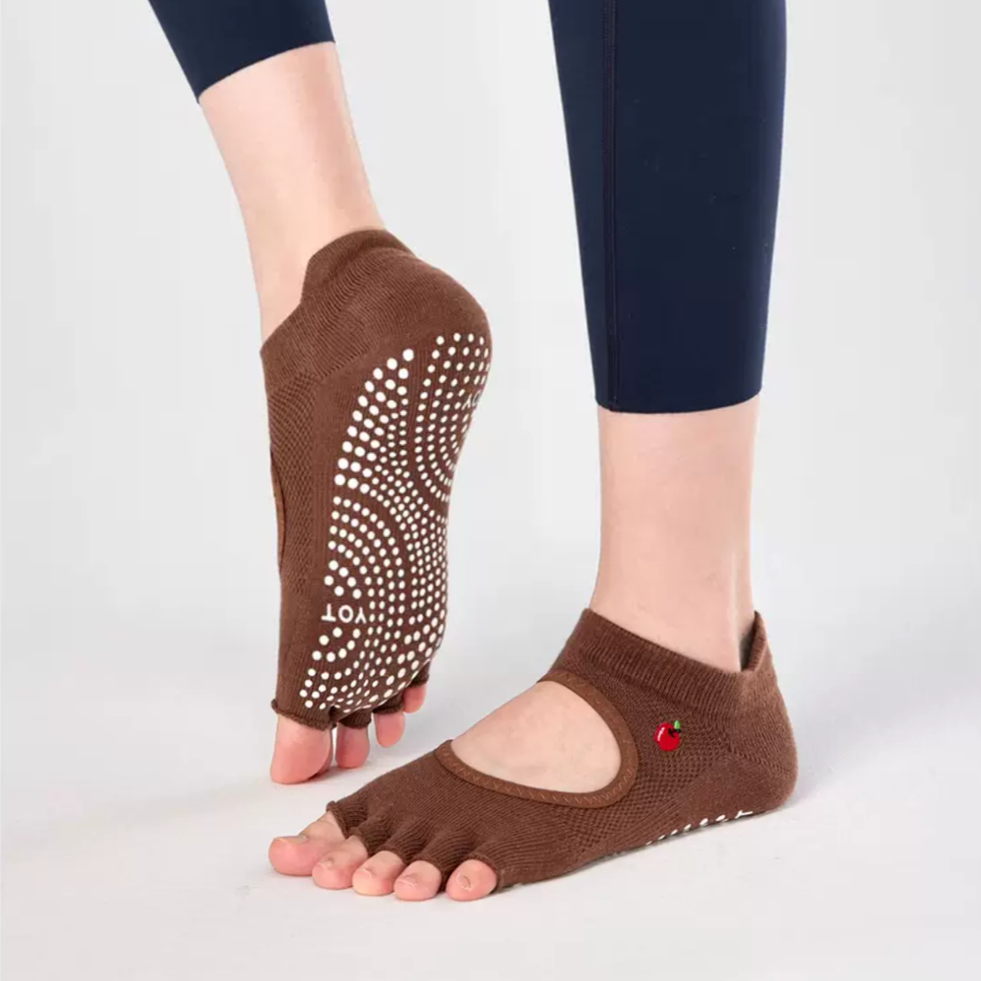 A pair of brown toeless non-slip grip socks with a pattern of white circles on the sole and a red cherry on the ankle support band.